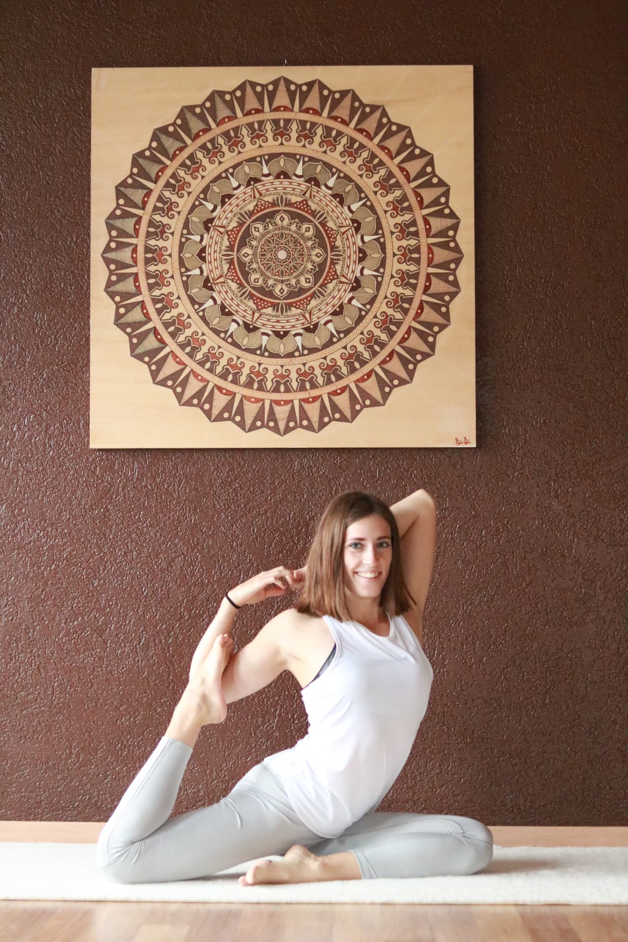 Madlen in einer Yogahaltung vor einem Mandala